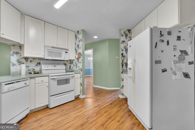 kitchen with white cabinets, white appliances, and light hardwood / wood-style flooring