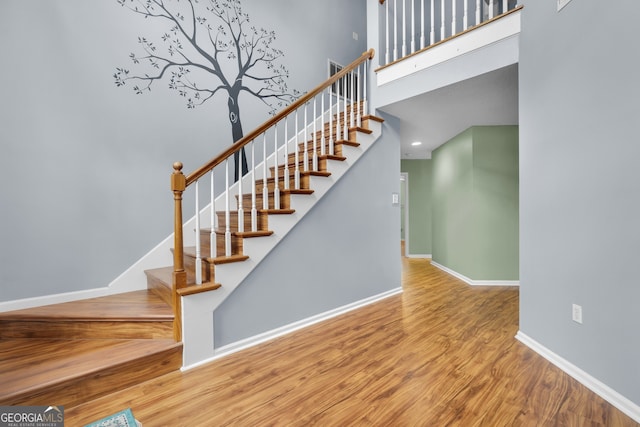 stairway featuring hardwood / wood-style flooring and a towering ceiling