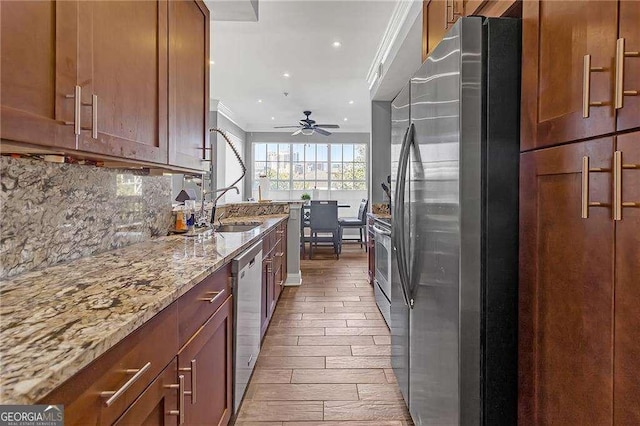 kitchen with sink, decorative backsplash, ornamental molding, light stone counters, and stainless steel appliances