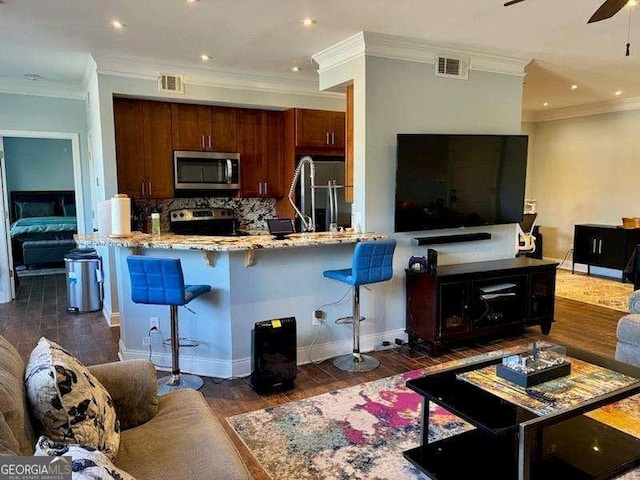 kitchen with dark hardwood / wood-style flooring, appliances with stainless steel finishes, a kitchen bar, and kitchen peninsula