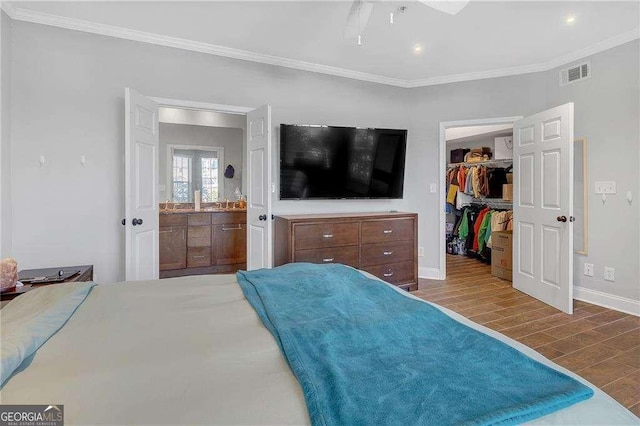 bedroom featuring ornamental molding, a walk in closet, ensuite bath, and a closet