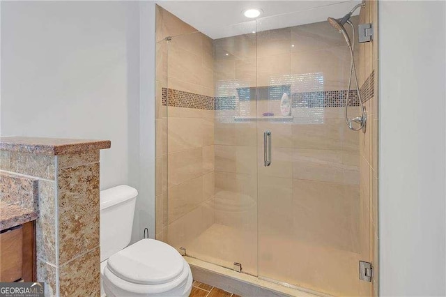 bathroom featuring vanity, a shower with shower door, and toilet