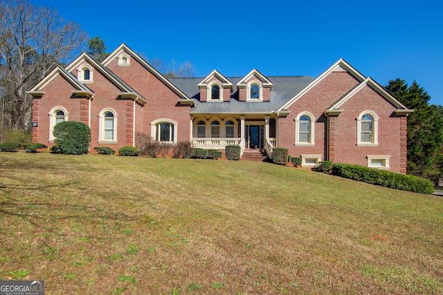 view of front of house with a front lawn, a porch, and brick siding