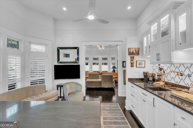 kitchen with sink, dark wood-type flooring, ceiling fan, dark stone countertops, and white cabinets