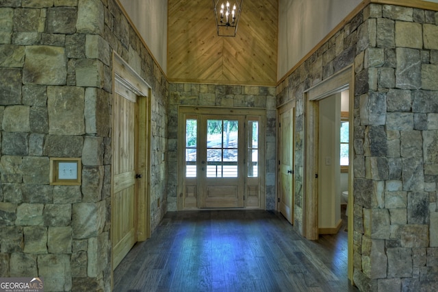 foyer with dark wood-type flooring, a towering ceiling, a chandelier, and a wealth of natural light