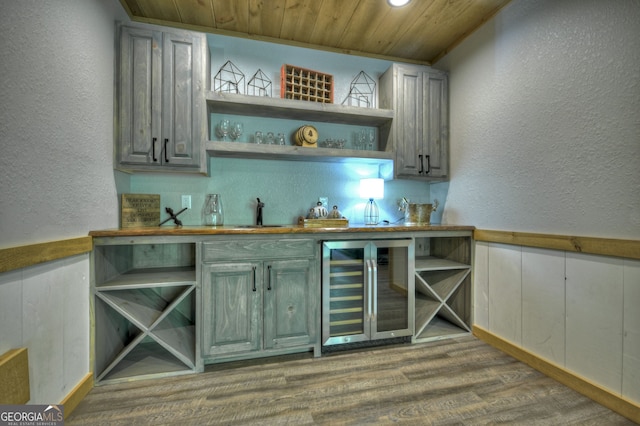 bar featuring wine cooler, hardwood / wood-style flooring, sink, and wooden ceiling