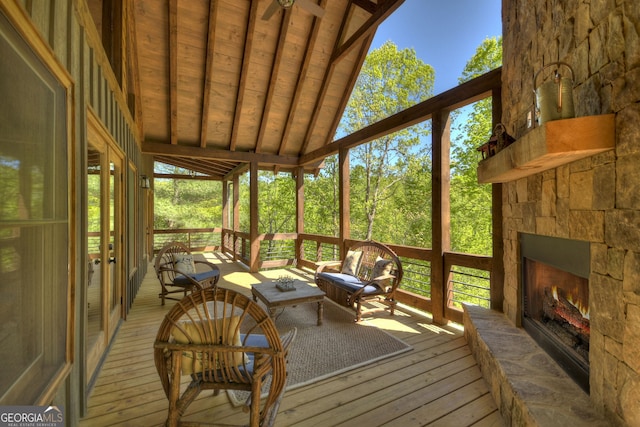 sunroom / solarium featuring vaulted ceiling with beams and a stone fireplace