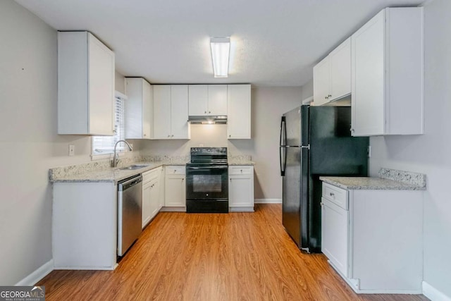 kitchen with sink, light stone counters, black appliances, light hardwood / wood-style floors, and white cabinets