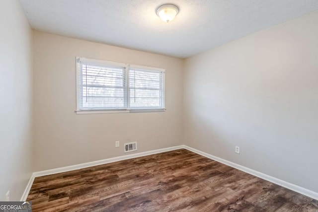 spare room with dark hardwood / wood-style flooring and a textured ceiling