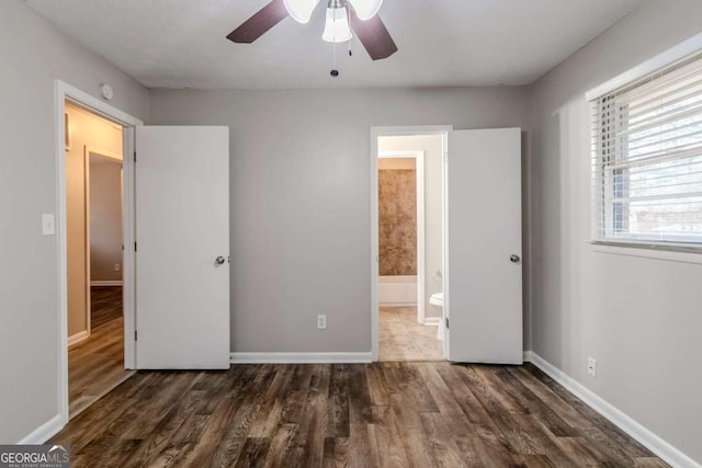 unfurnished bedroom featuring dark hardwood / wood-style floors, connected bathroom, and ceiling fan