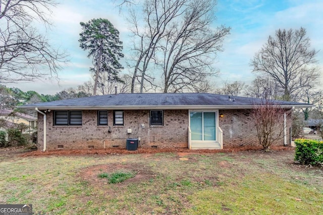 rear view of house with central AC and a lawn