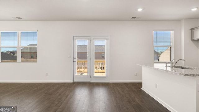 unfurnished dining area featuring dark wood-type flooring, plenty of natural light, and sink