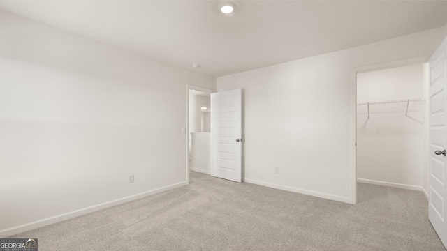 unfurnished bedroom featuring light colored carpet, a spacious closet, and a closet