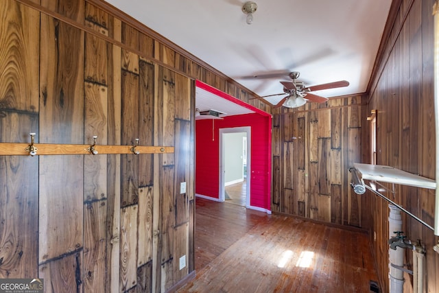 corridor featuring hardwood / wood-style flooring, wooden walls, and baseboards