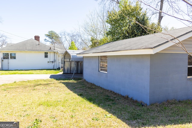 view of side of property featuring a detached carport, a lawn, and concrete block siding