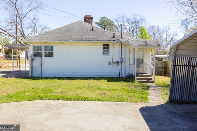 rear view of house with fence, a lawn, roof with shingles, and a chimney