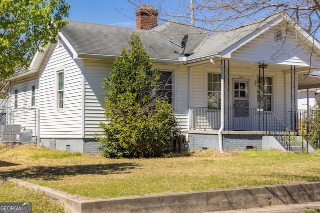 exterior space with covered porch, a front yard, a shingled roof, crawl space, and a chimney