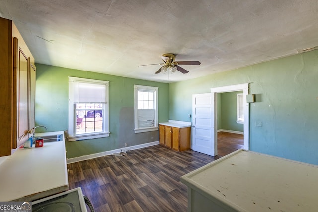 interior space featuring baseboards, ceiling fan, light countertops, brown cabinets, and dark wood-style flooring