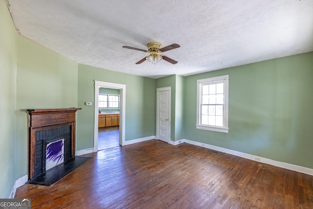 unfurnished living room with baseboards, hardwood / wood-style floors, a fireplace, a textured ceiling, and a ceiling fan