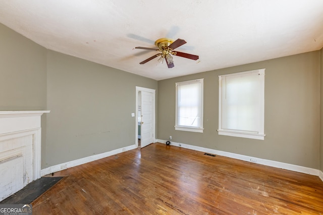 unfurnished living room with a ceiling fan, wood finished floors, visible vents, and baseboards