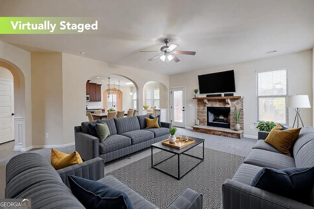 carpeted living area with arched walkways, a healthy amount of sunlight, and visible vents