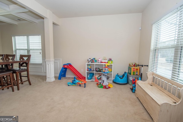 playroom featuring light colored carpet, beam ceiling, and decorative columns