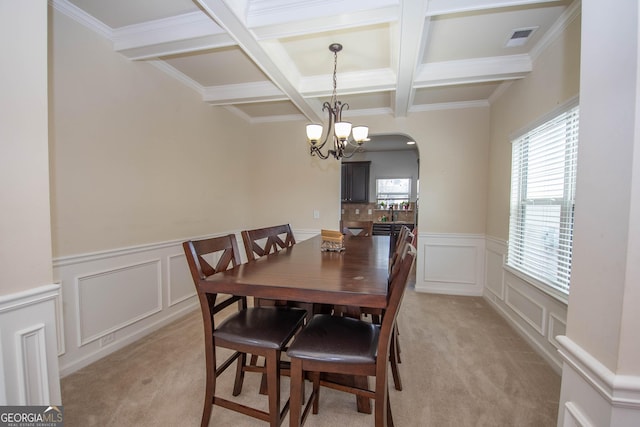 carpeted dining space with coffered ceiling, ornamental molding, a chandelier, and beamed ceiling