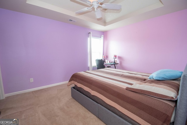 carpeted bedroom with ceiling fan and a tray ceiling