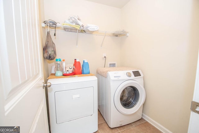 clothes washing area featuring light tile patterned floors and washing machine and dryer