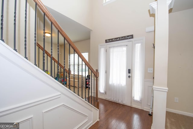 foyer featuring ornate columns, dark hardwood / wood-style floors, and a towering ceiling