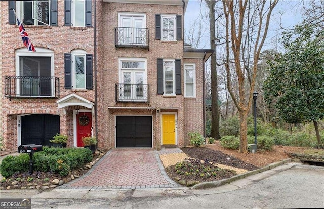 multi unit property featuring decorative driveway, brick siding, and an attached garage