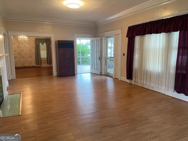 unfurnished living room featuring ornamental molding, wood finished floors, and an inviting chandelier