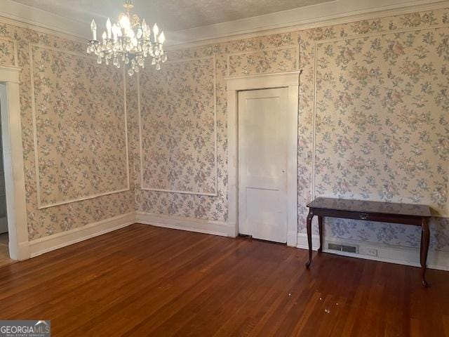 interior space featuring crown molding, dark wood-type flooring, a chandelier, and wallpapered walls