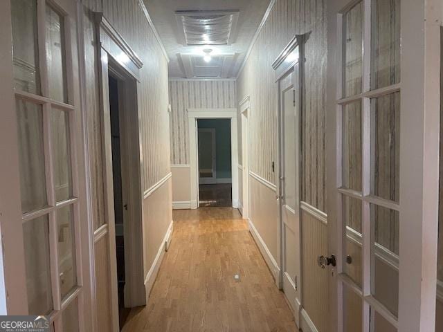 hallway with wallpapered walls, attic access, ornamental molding, and wood finished floors