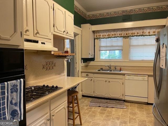 kitchen featuring light countertops, freestanding refrigerator, a sink, dishwasher, and under cabinet range hood