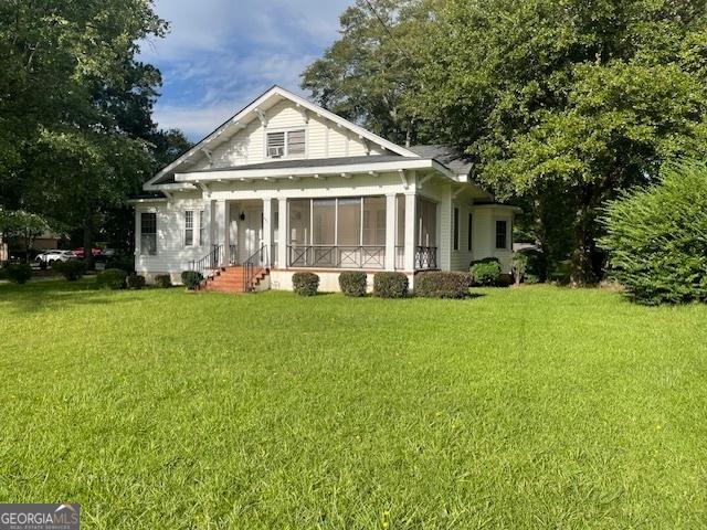 rear view of property featuring a sunroom and a lawn