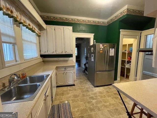 kitchen featuring a sink, white cabinets, light countertops, ornamental molding, and freestanding refrigerator