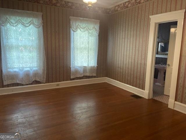 spare room with wood finished floors, baseboards, and wallpapered walls