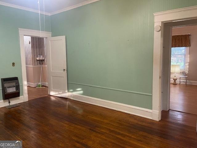 unfurnished room with baseboards, ornamental molding, wood finished floors, and heating unit