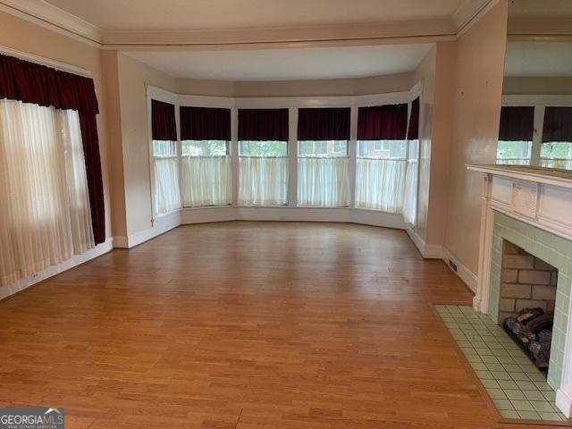 unfurnished living room featuring a healthy amount of sunlight, light wood-style flooring, and a tiled fireplace