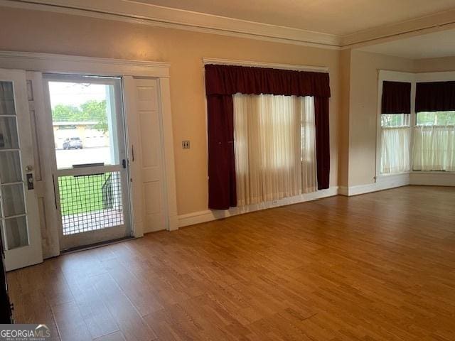 interior space with baseboards, ornamental molding, and wood finished floors