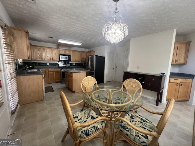 dining room featuring sink, a textured ceiling, and a chandelier