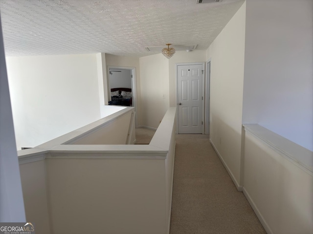 hall featuring light colored carpet and a textured ceiling