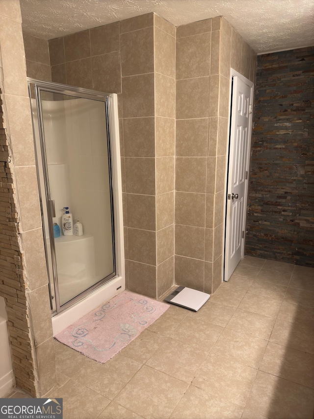 bathroom with a shower with shower door, tile patterned floors, and a textured ceiling