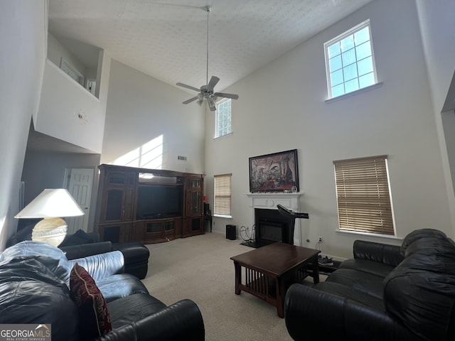 living room with ceiling fan, plenty of natural light, light carpet, and a textured ceiling