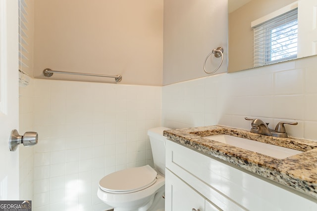 bathroom with vanity, tile walls, and toilet