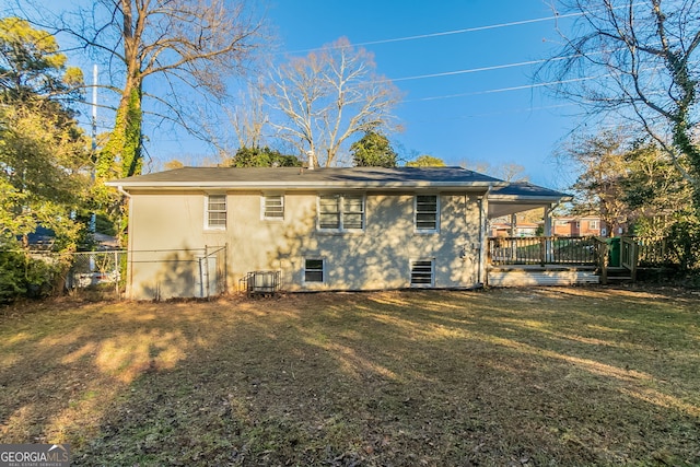 rear view of property featuring a yard, cooling unit, and a deck