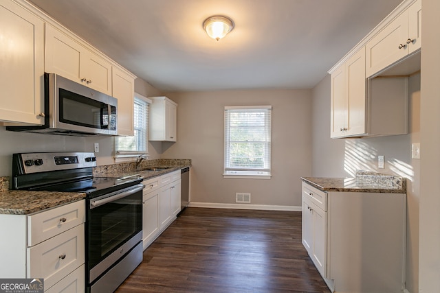 kitchen featuring white cabinetry, plenty of natural light, dark stone counters, and appliances with stainless steel finishes