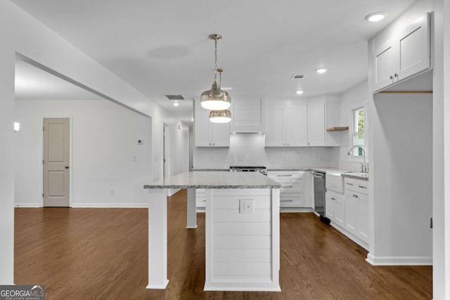 kitchen with white cabinetry, stainless steel appliances, light stone countertops, a kitchen island, and decorative light fixtures