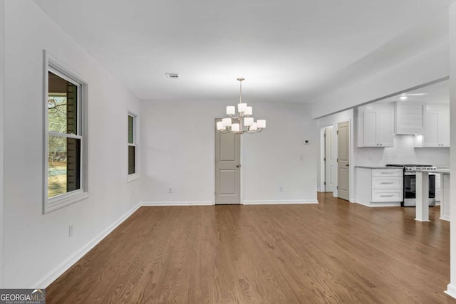 unfurnished dining area featuring a notable chandelier and wood-type flooring